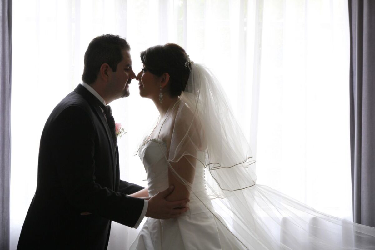 Ma Vidéo de Mariage A bride and groom sharing an intimate moment by the window, showcasing love and elegance.